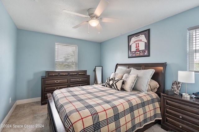 carpeted bedroom with ceiling fan and a textured ceiling