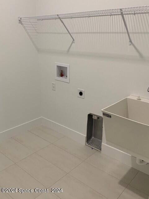 laundry room with a sink, electric dryer hookup, laundry area, light tile patterned floors, and hookup for a washing machine