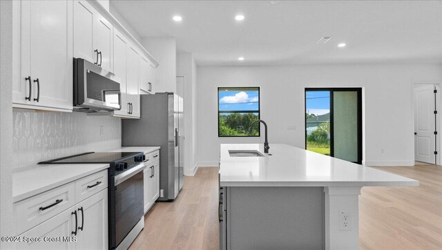 566 Hamy St, Palm Bay, FL 32908 - kitchen featuring stainless steel microwave, a sink, electric range, an island with sink, and light countertops