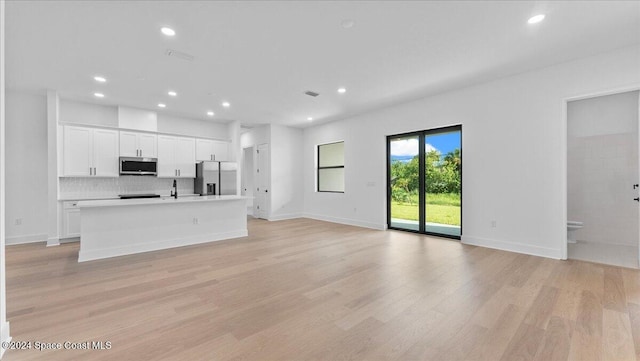 unfurnished living room featuring sink and light hardwood / wood-style flooring