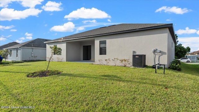 back of property with a yard and central AC