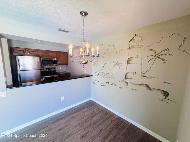 kitchen with a textured ceiling, a chandelier, decorative light fixtures, dark wood-type flooring, and appliances with stainless steel finishes