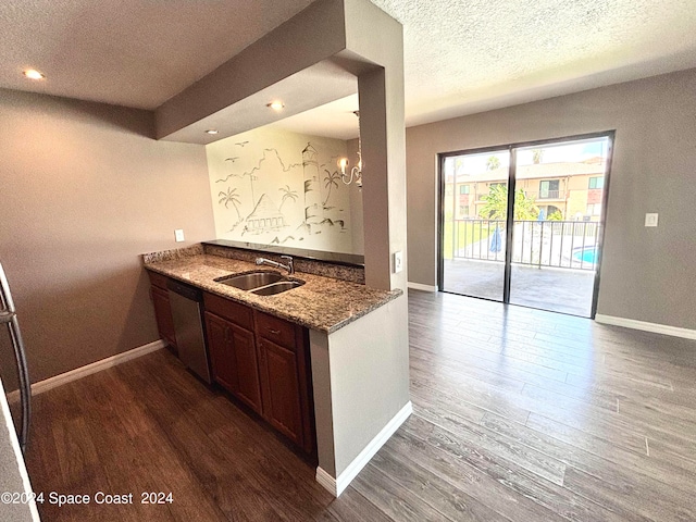 kitchen featuring a textured ceiling, dark hardwood / wood-style flooring, light stone counters, sink, and stainless steel dishwasher