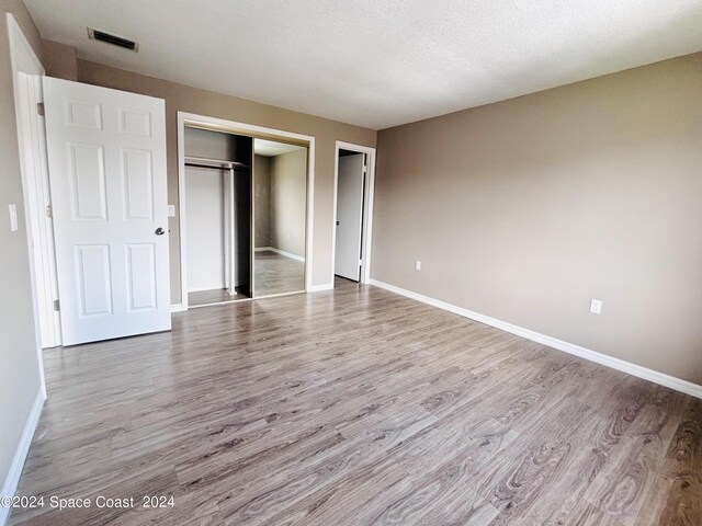 unfurnished bedroom featuring a closet, hardwood / wood-style flooring, and a textured ceiling