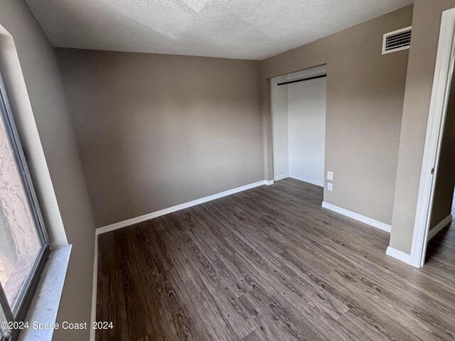 unfurnished bedroom with hardwood / wood-style floors, a closet, and a textured ceiling