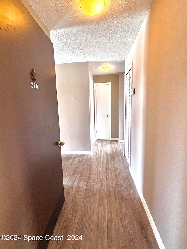 hall with wood-type flooring and a textured ceiling