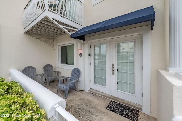 view of exterior entry featuring a balcony and french doors