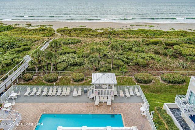 view of pool with a view of the beach, a deck with water view, and a gazebo