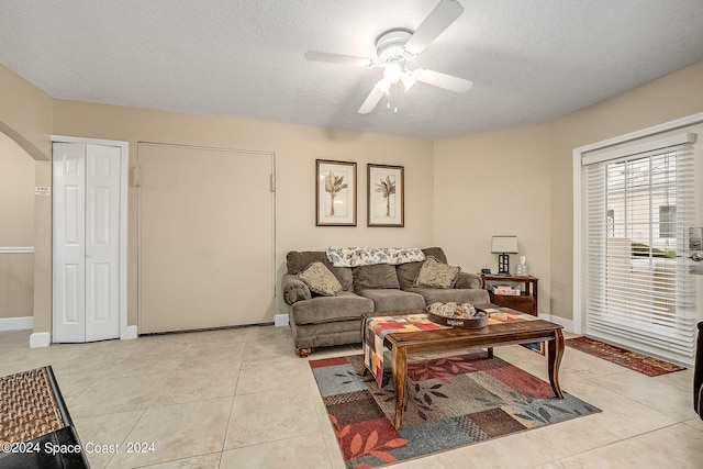 living room with a textured ceiling, light tile patterned flooring, and ceiling fan