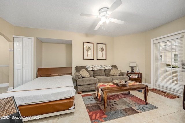 tiled living room with a textured ceiling and ceiling fan