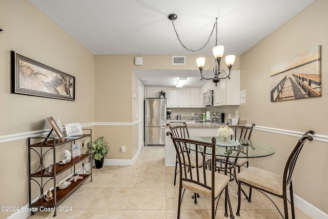 dining room featuring a textured ceiling, light tile patterned floors, and a notable chandelier