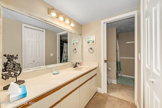 bathroom with tile patterned flooring, a textured ceiling, and vanity