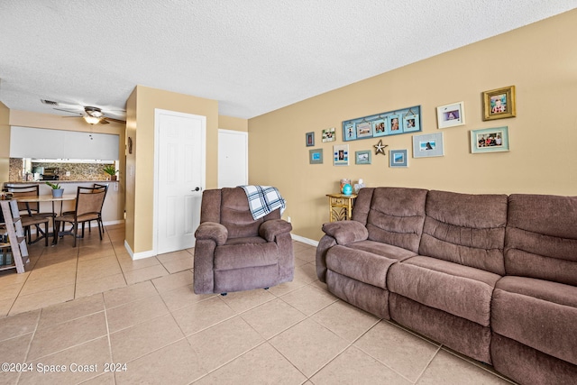 living room with ceiling fan, a textured ceiling, and light tile patterned floors