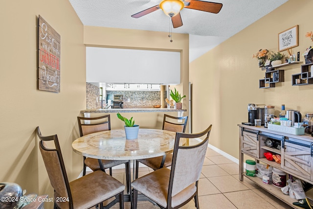 dining area featuring ceiling fan, light tile patterned floors, and a textured ceiling