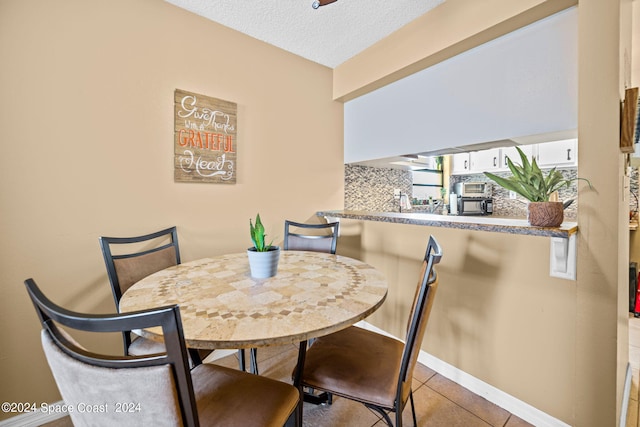 dining area featuring a textured ceiling and light tile patterned floors