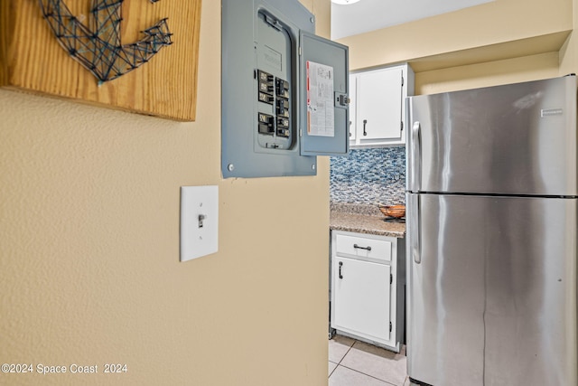 kitchen featuring electric panel, tasteful backsplash, white cabinets, stainless steel refrigerator, and light tile patterned floors