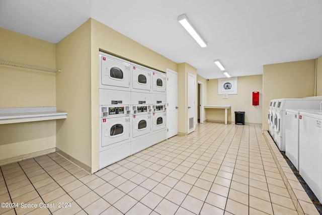 laundry area with stacked washer / dryer, washer and clothes dryer, and light tile patterned floors