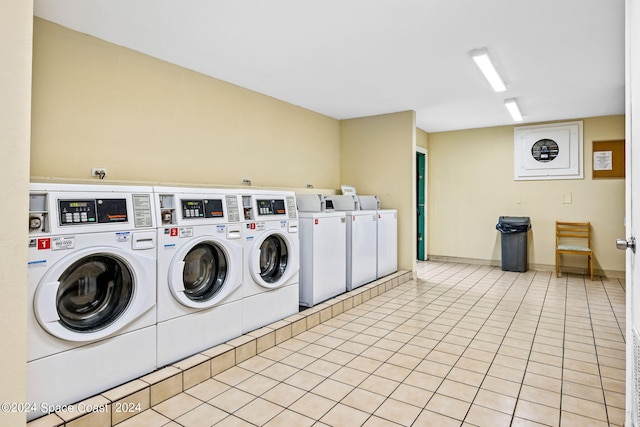 clothes washing area with washer and clothes dryer and light tile patterned flooring