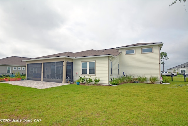 back of property with a sunroom, a yard, and a patio area