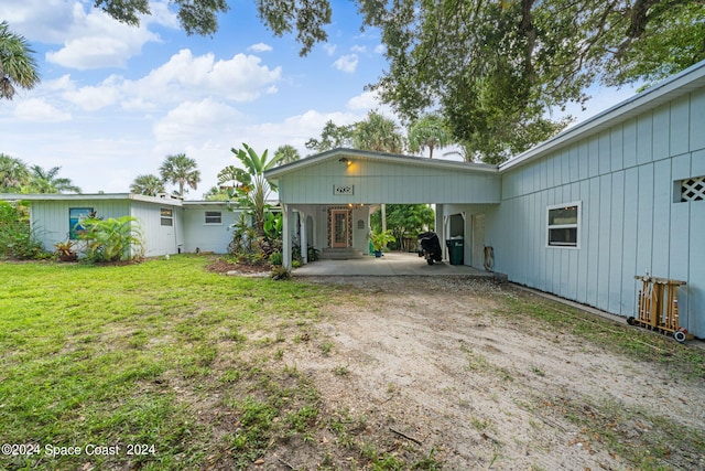 rear view of house with a lawn and a carport