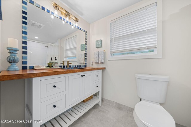 bathroom featuring tile patterned floors, a shower with curtain, toilet, and vanity