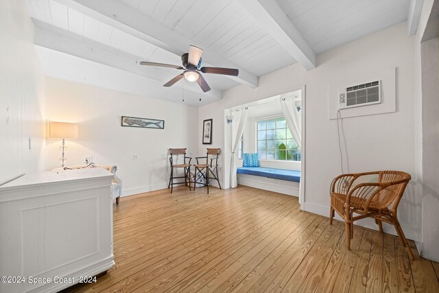 sitting room featuring beamed ceiling, a wall unit AC, ceiling fan, and light hardwood / wood-style floors