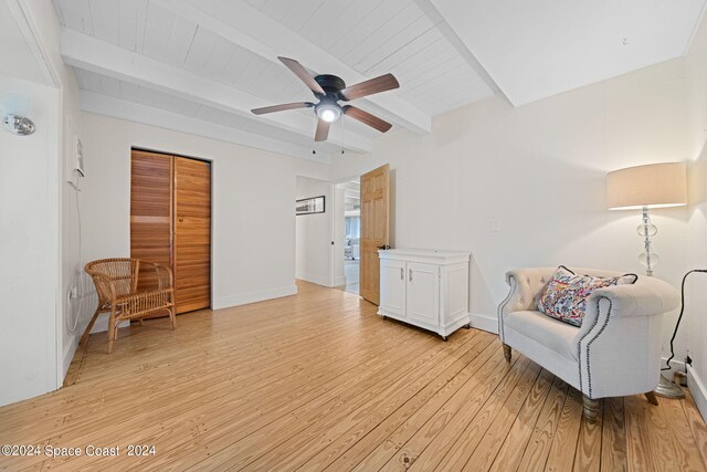 living area featuring ceiling fan, beamed ceiling, and light wood-type flooring