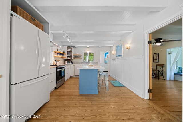 kitchen featuring white appliances, white cabinetry, ceiling fan, a kitchen breakfast bar, and beam ceiling