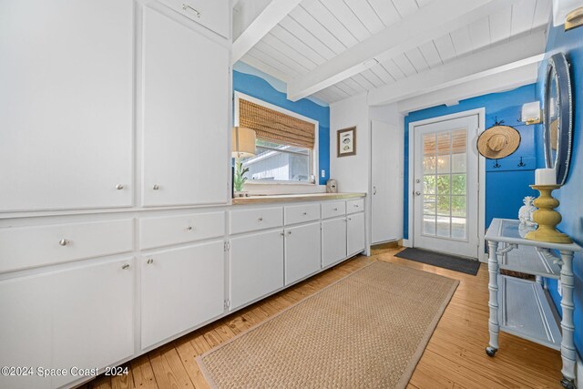 kitchen with light hardwood / wood-style flooring, beam ceiling, white cabinetry, and a healthy amount of sunlight