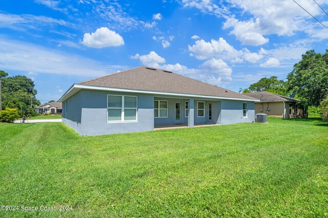 rear view of property featuring central air condition unit and a lawn