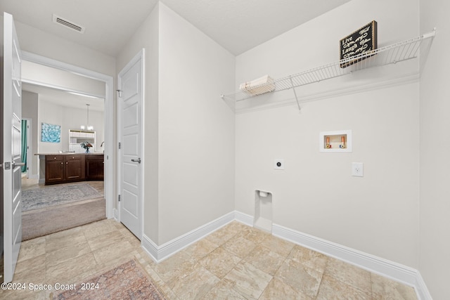 washroom featuring hookup for a washing machine, an inviting chandelier, and hookup for an electric dryer