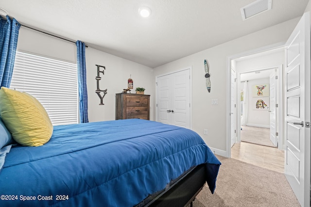 bedroom featuring a textured ceiling, a closet, and light carpet