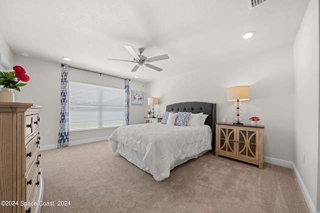 bedroom featuring ceiling fan, light carpet, and a textured ceiling