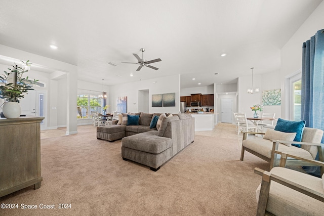 living room with ceiling fan with notable chandelier, light colored carpet, and plenty of natural light