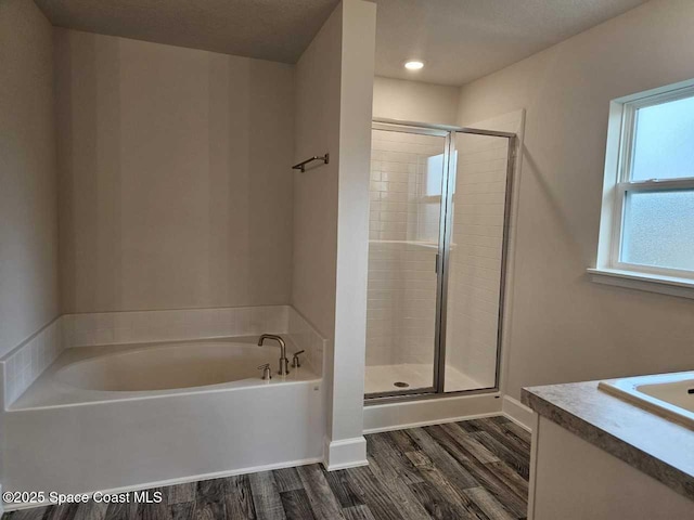full bath with a bath, vanity, wood finished floors, a stall shower, and baseboards