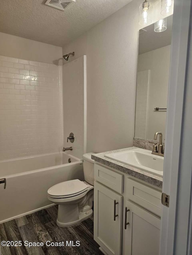 full bath with a textured ceiling, vanity, visible vents, toilet, and wood finished floors