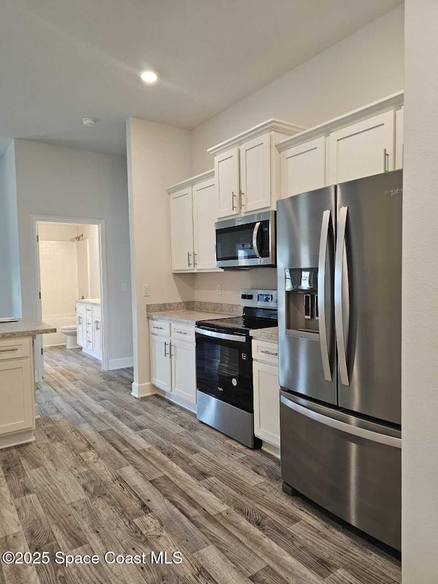 kitchen with recessed lighting, light countertops, white cabinets, stainless steel appliances, and wood finished floors