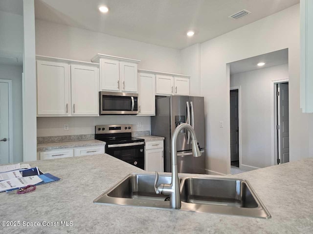 kitchen featuring visible vents, white cabinets, a sink, light countertops, and appliances with stainless steel finishes