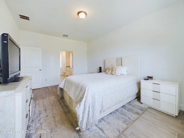 bedroom with light hardwood / wood-style flooring and ensuite bath