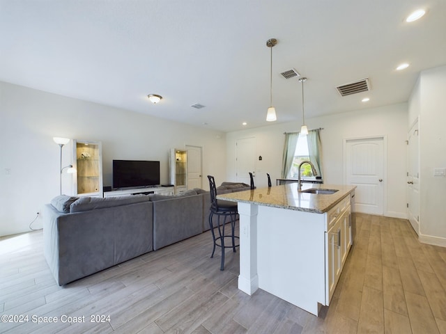 kitchen with light hardwood / wood-style flooring, a center island with sink, and sink