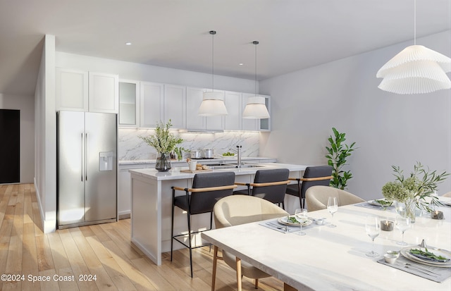 kitchen featuring light wood-type flooring, pendant lighting, tasteful backsplash, stainless steel refrigerator with ice dispenser, and white cabinets