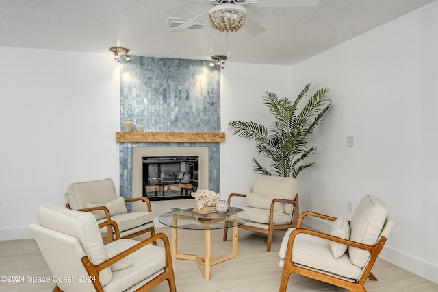 living room featuring ceiling fan, a textured ceiling, and light hardwood / wood-style floors