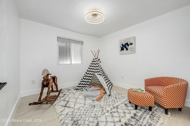 game room with a textured ceiling and light hardwood / wood-style flooring