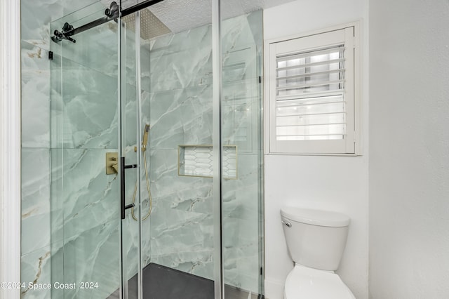 bathroom with a textured ceiling, toilet, and an enclosed shower