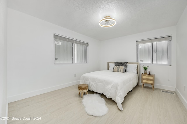 bedroom with light wood-type flooring and a textured ceiling