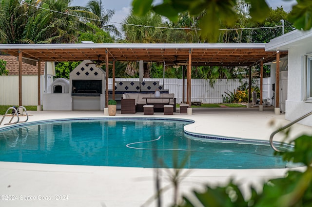 view of swimming pool featuring a patio, an outdoor kitchen, outdoor lounge area, and a gazebo