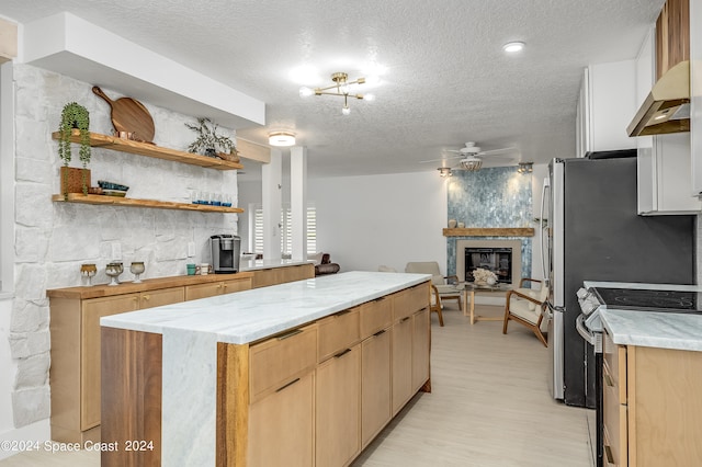 kitchen featuring a textured ceiling, electric stove, ceiling fan, and a large fireplace