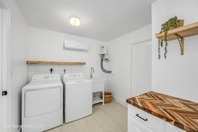 washroom featuring an AC wall unit, light hardwood / wood-style floors, separate washer and dryer, and a textured ceiling