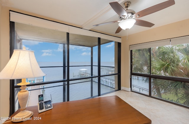 unfurnished sunroom featuring ceiling fan and a water view