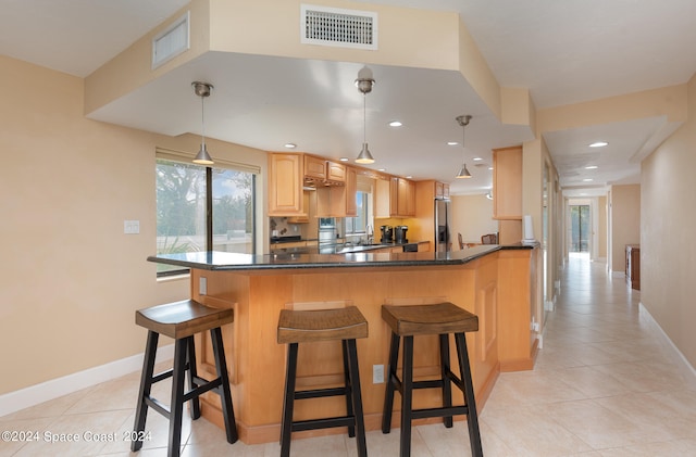 kitchen with plenty of natural light, kitchen peninsula, a kitchen breakfast bar, and hanging light fixtures